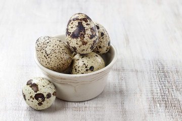Obraz premium Quail eggs in ceramic bowl standing on rustic wooden table