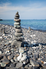 Colorful pebbles touching wave at beautiful rock island