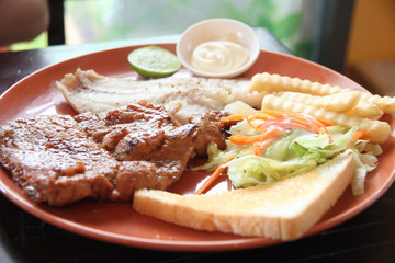 grilled pork steak with french fries and toast.