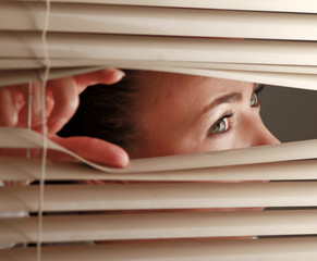 Portrait of a woman looking through out the blinds