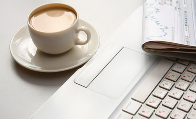 Cup of coffee near press and laptop.