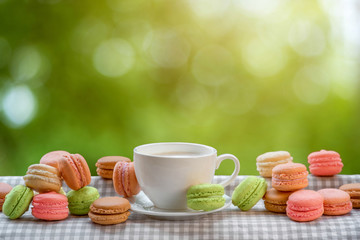 Colorful macaroons with cup of coffee on the napkin on blurred g