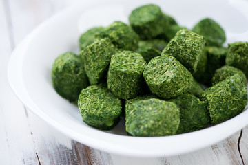 Cubes of chopped spinach in a glass plate, horizontal shot