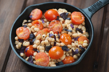 Roasted cherry tomatoes and white beans in a frying pan