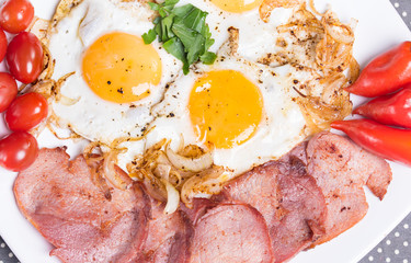 Breakfast with fried eggs beacon onion and fresh tomatoes