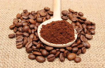 Ground coffee on wooden scoop and grains coffee