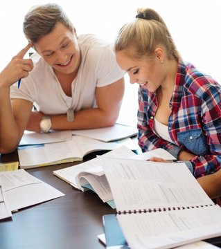 Young students couple preparing for exams behind table