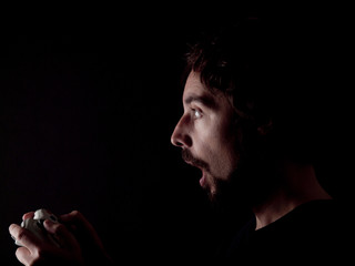 Low key image of a bearded man playing videogames