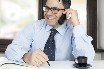 Uomo in ufficio contento al telefono