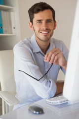 Fototapeta premium Casual businessman smiling at camera at his desk