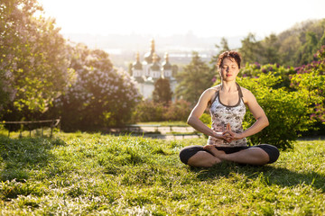 Young Caucasian woman meditating in lotus position outdoors