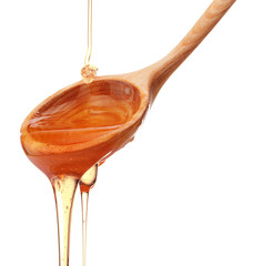 Honey dripping from a wooden honey dipper isolated on white back