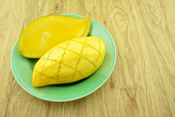 Slice half ripe mango on green dish