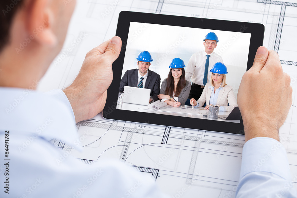Poster architect video conferencing with team through digital tablet