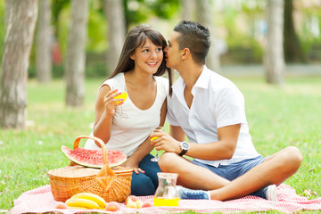 Young happy couple having picnic in the park.