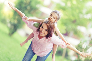 Playful mother and little daughter enjoying in nature.