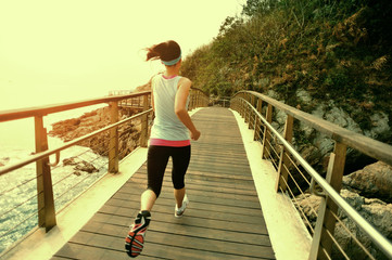 Obraz premium fitness woman running at seaside wooden bridge