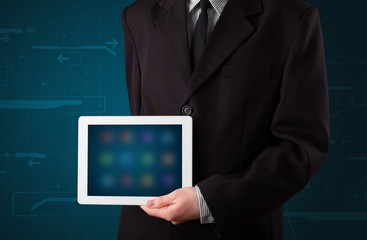 Businessman holding a white modern tablet with blurry apps