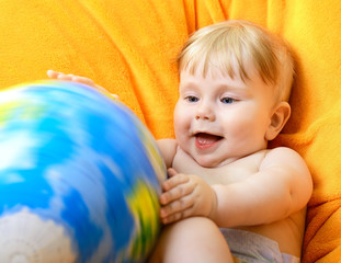 Happy baby playing with terrestrial globe on an orange plaid
