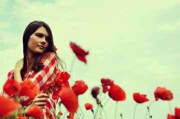Naklejka premium Portrait of calm beautiful girl through a poppy field, summer ou