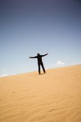 Fototapeta na wymiar jubelnder Mann auf einsamer Sanddüne