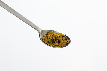 bee pollen grains with spoon on white background