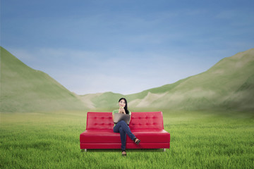 Attractive woman having coffee on red sofa outdoor