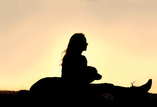Silhouette of Girl Sitting OUtside with Large Dog