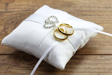 goldene Trauringe auf weißem Ringkissen	