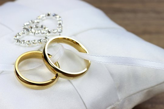 goldene Trauringe auf wei&szlig;em Ringkissen	