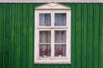Obraz na płótnie Canvas White window of an old wooden green cabin