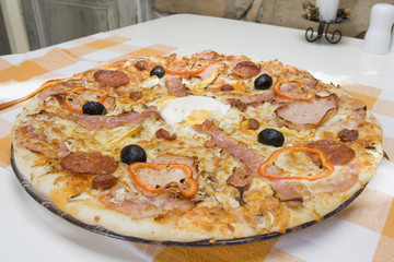 Pizza with egg, peppers and sausage on the table.