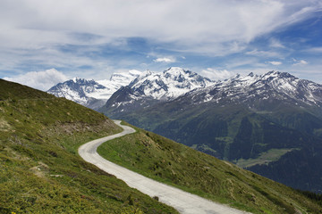 Fototapeta na wymiar A mountain road winding towards spectacular mountains