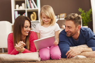 Loving family using digital tablet on carpet