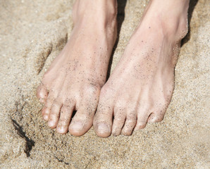 women's feet in a bright golden sand
