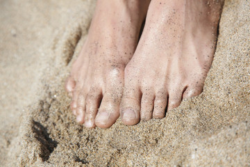 women's feet in a bright golden sand