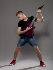 Young guitarist plays on the electric guitar with bright emotion