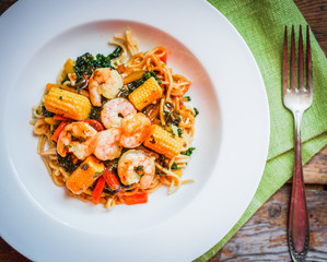 Italian pasta with shrimps and vegetables on wooden background