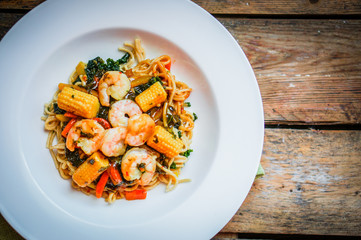 Italian pasta with shrimps and vegetables on wooden background