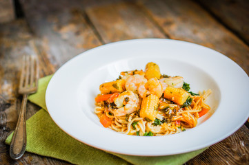 Italian pasta with shrimps and vegetables on wooden background