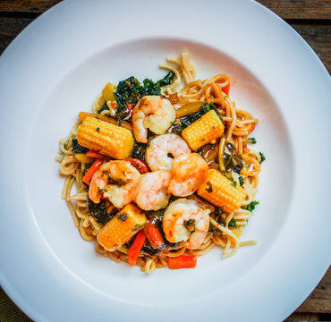 Italian pasta with shrimps and vegetables on wooden background