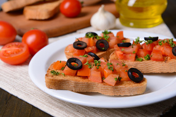 Delicious bruschetta with tomatoes on plate on table close-up