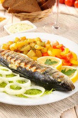 Delicious grilled fish on plate on table close-up