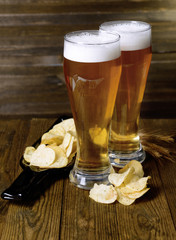 Glasses of beer with snack on table on wooden background