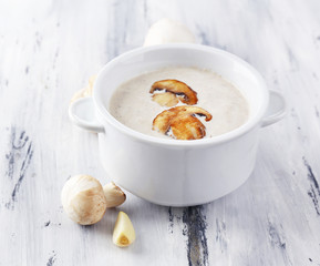 Mushroom soup in pot, on wooden background