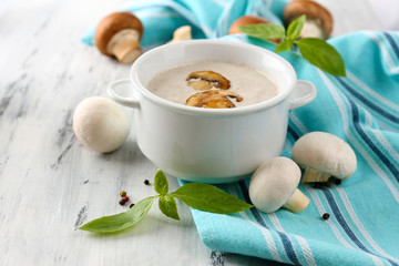 Mushroom soup in white pot, on napkin,  on wooden background