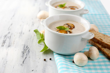 Mushroom soup in white pots, on napkin,  on wooden background