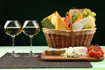 Basket with different cheese and glasses of wine
