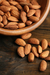 Almonds in bowl on color wooden background