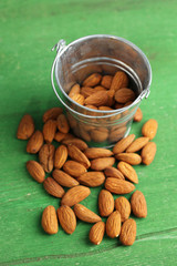 Almonds in bucket on color wooden background